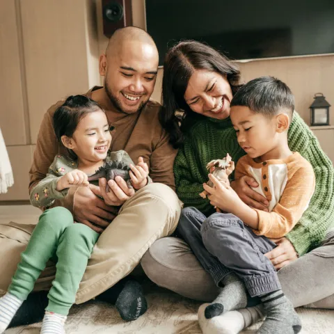 Happy family sitting on the floor in their living room.