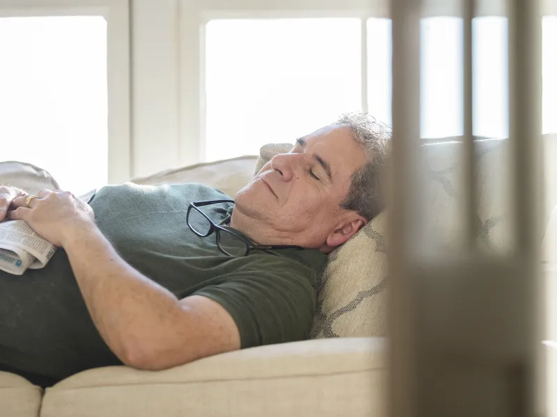 An adult Caucasian man takes an afternoon nap on the couch.