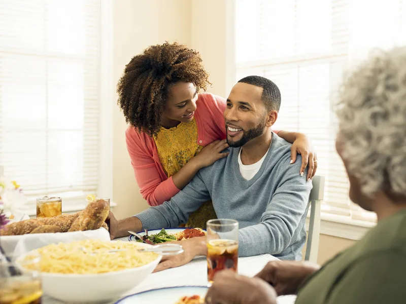 An African American family gathers around the dinner table for a meal of spaghetti.