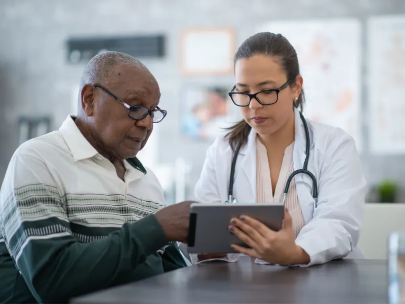 A Provider Goes Over a Patient's Chart with Him on a Tablet.