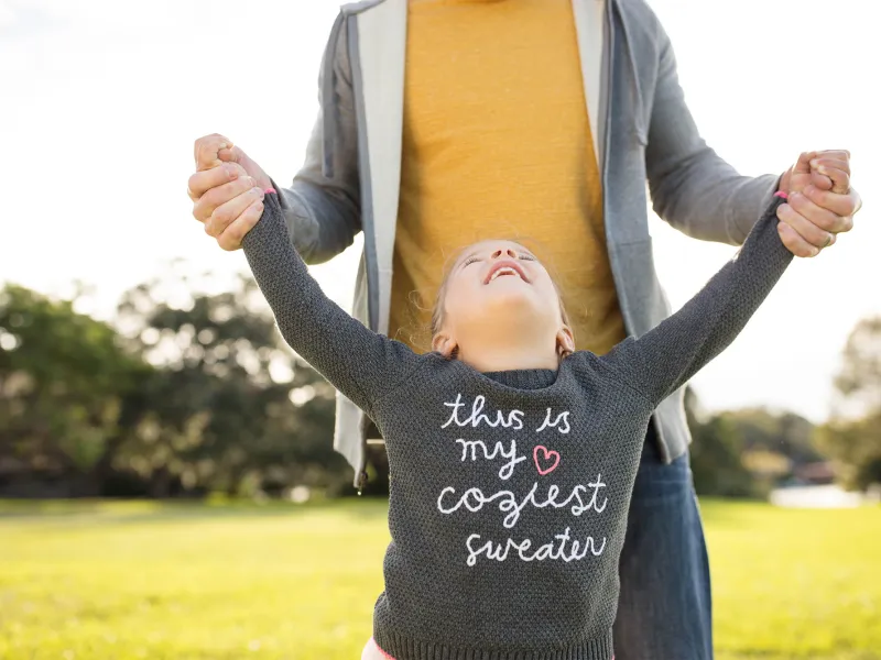 Daughter smiling looking up to father outside