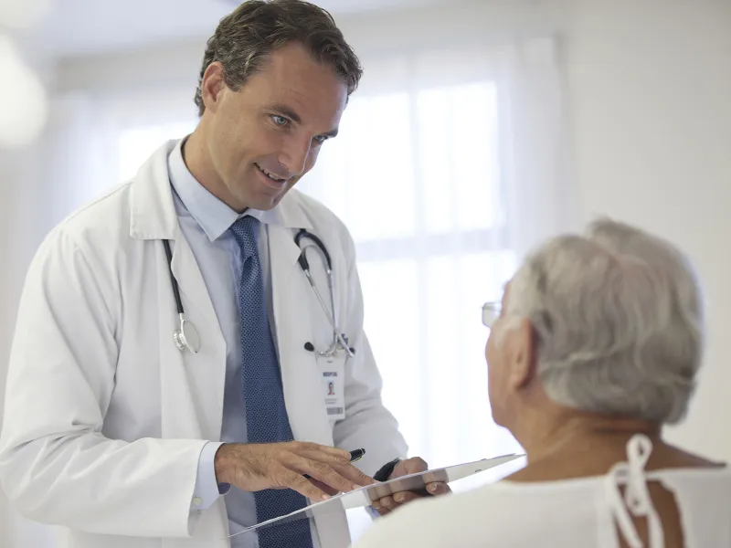 A Caucasian male doctor consults with a female patient at the hospital.