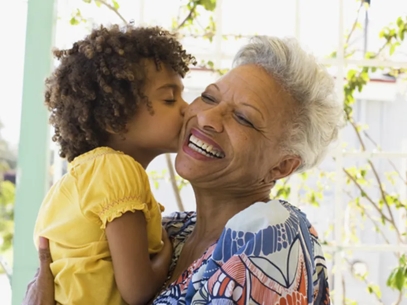 A grandmother receives a kiss on the cheek from her granddaughter.