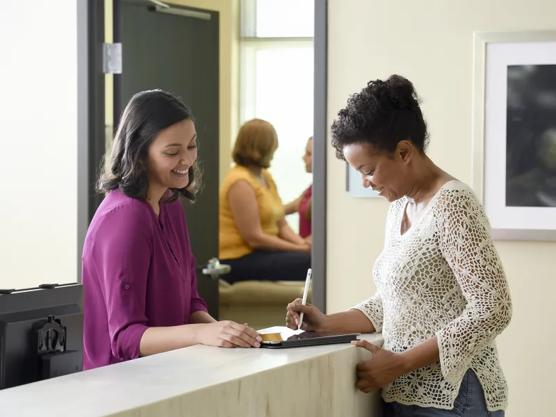 A female patient fills out paperwork for her doctor appointment.