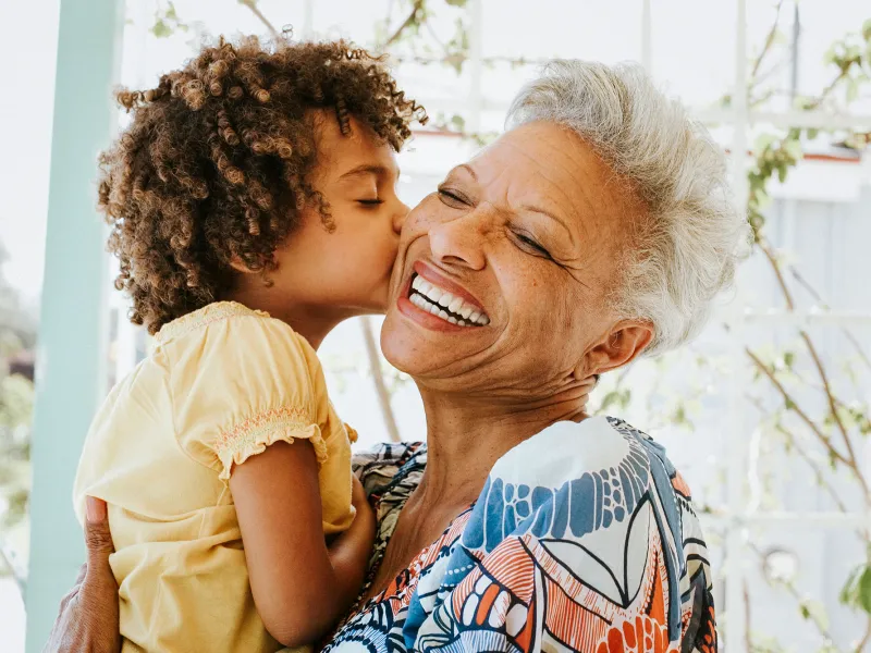 Grandmother getting a kiss from her granddaughter.