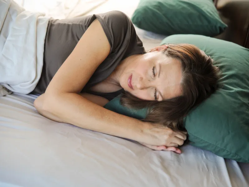A woman sleeps soundly on her side in bed