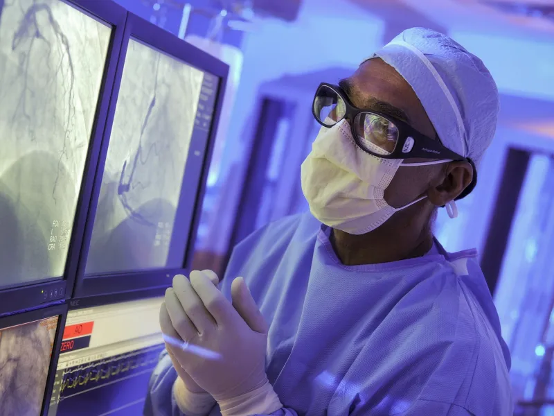 A surgeon at AHS Carrolwood studies a patient's imaging in the operating room, preparing for a procedure