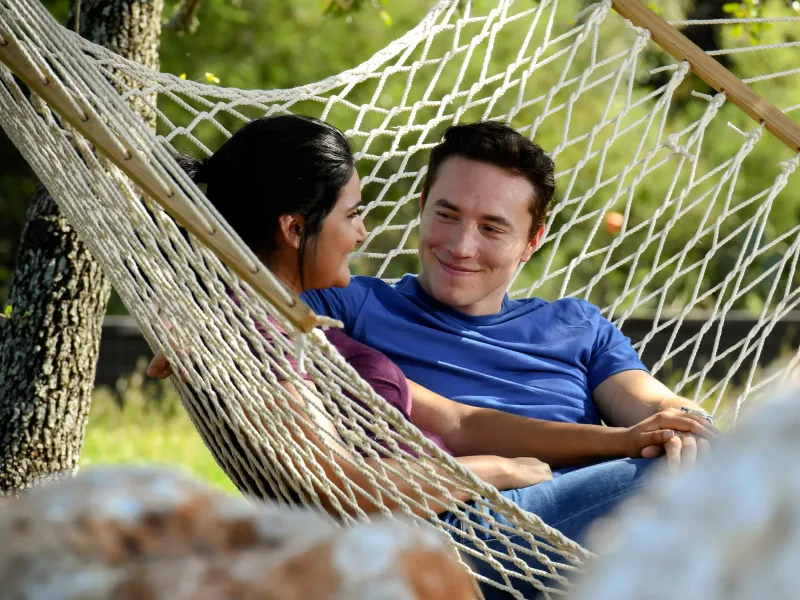 Couple sitting on a hammock outside.