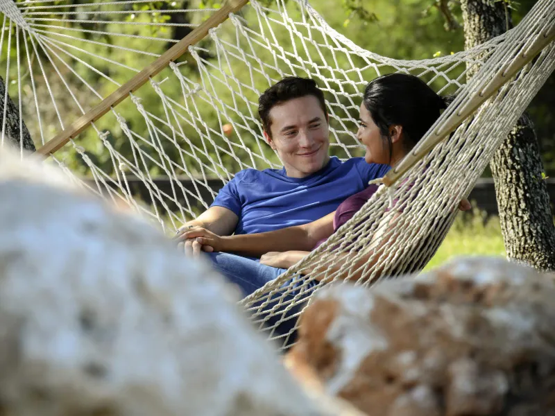Couple sitting in a hammock outdoors.
