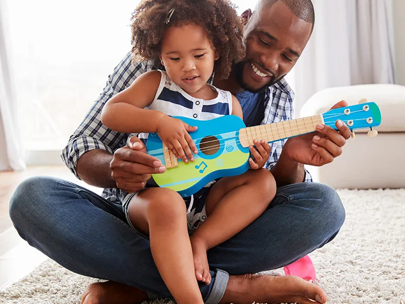 dad daughter playing toy guitar