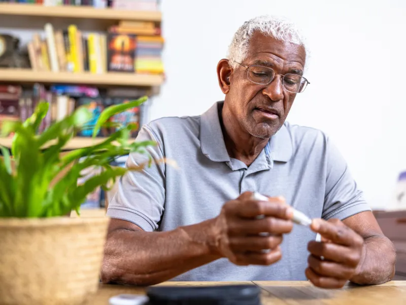 An older man using a blood sugar measuring device