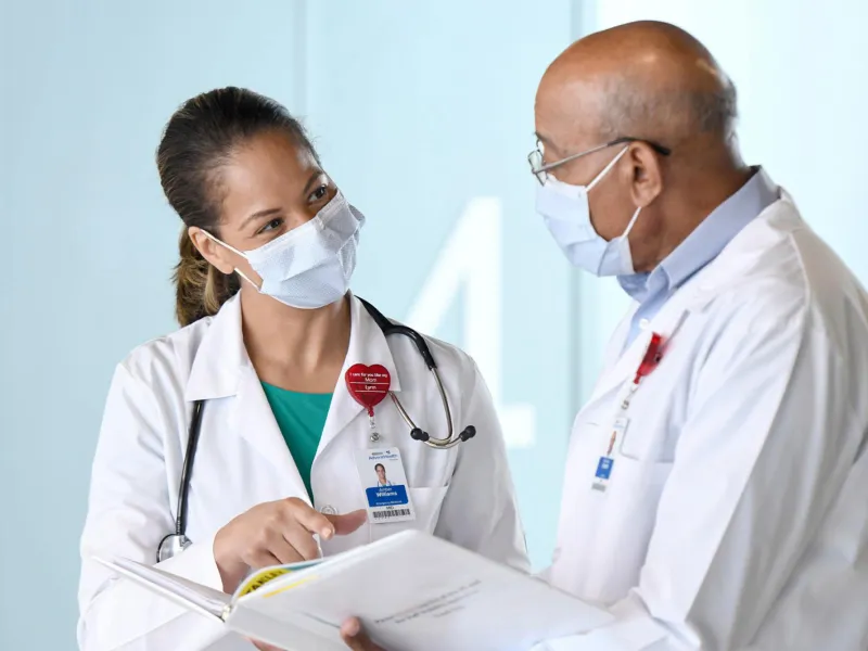 Two doctors talking while wearing masks.