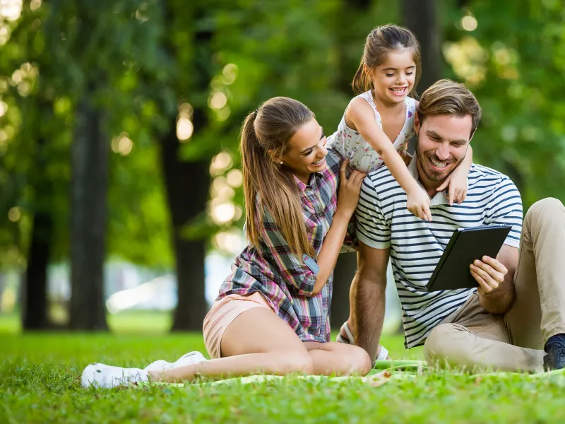 Happy family in park reading a tablet 