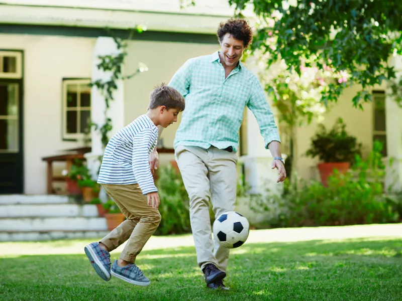Father and son playing soccer.