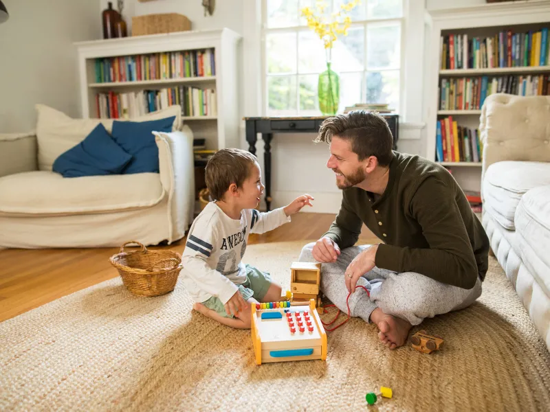 A dad playing a board game with his son in the family room.