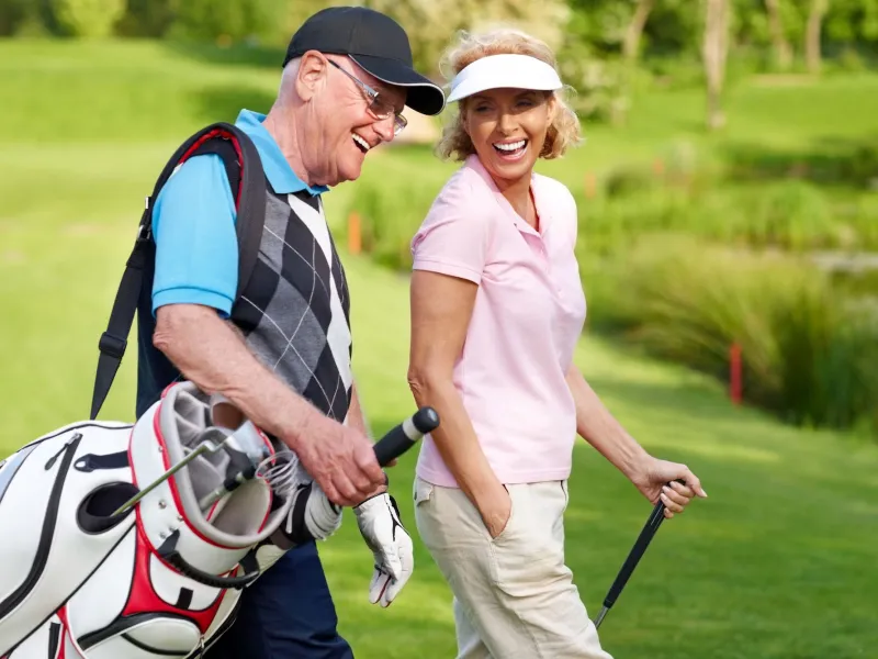 A couple walks the course between holes while golfing.