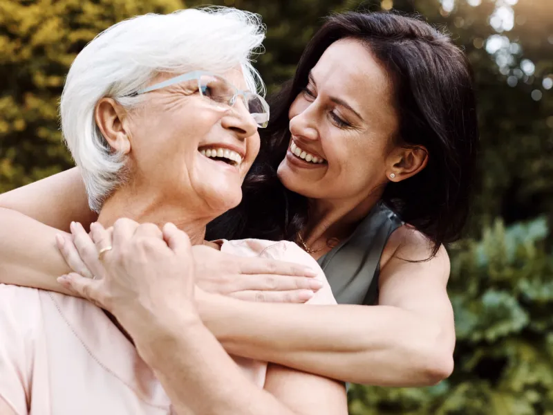 An adult woman hugs her mother.