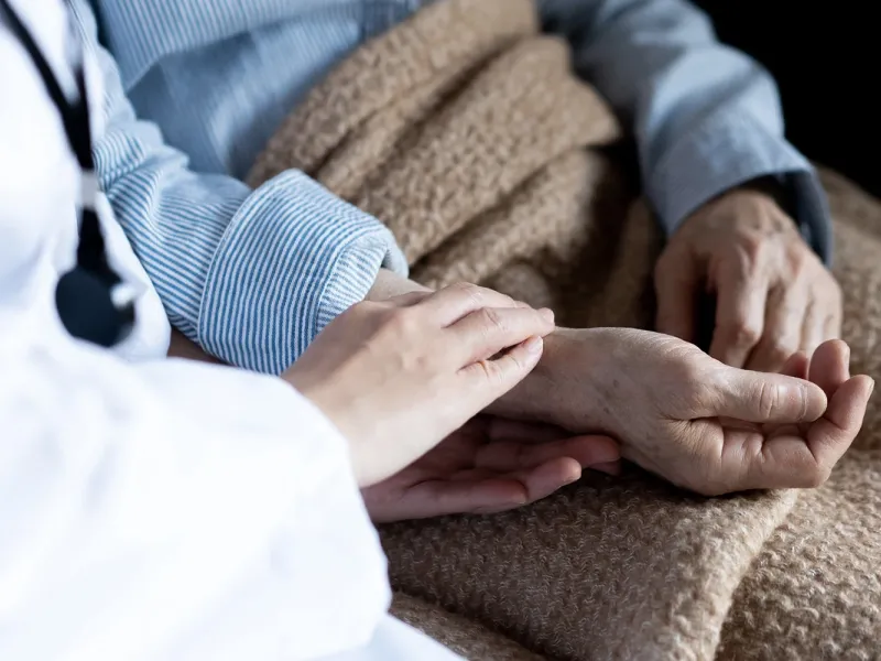 Close up of a physician's and hospice patient's hands.