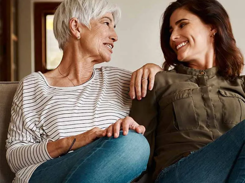 Elderly woman with adult daughter on couch