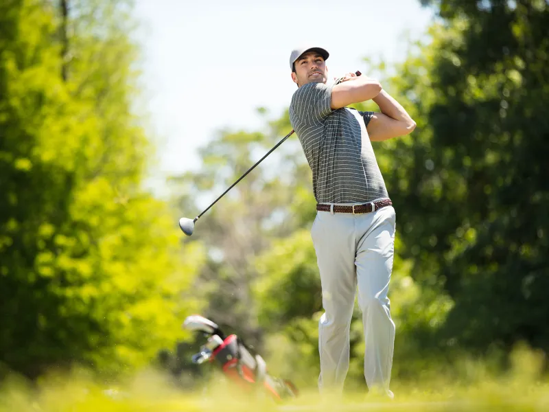 A man playing golf on the golf course on a sunny day.