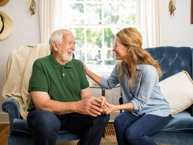 A daughter having a conversation with her elderly father in the family room.
