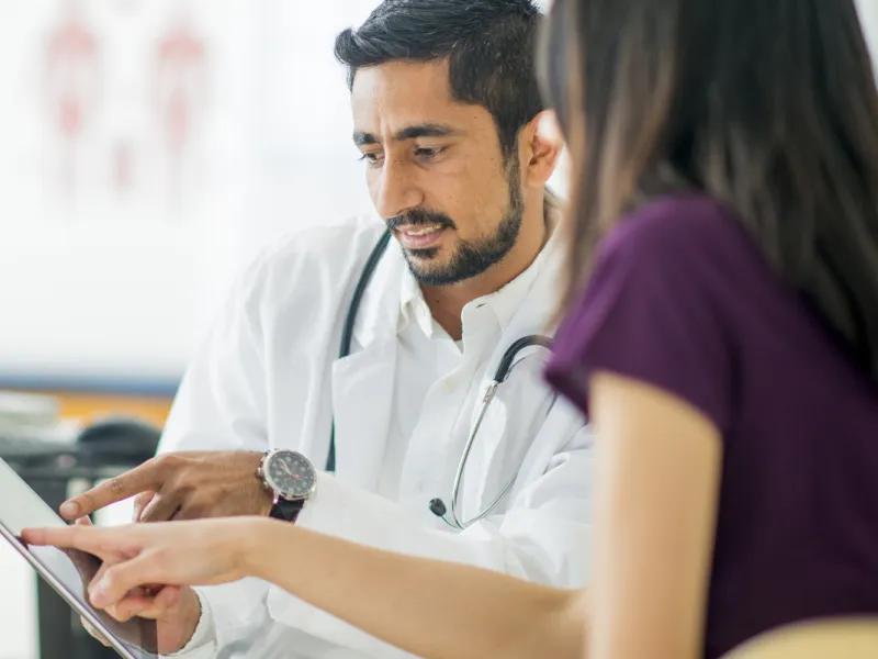 A doctor and a patient read a tablet.