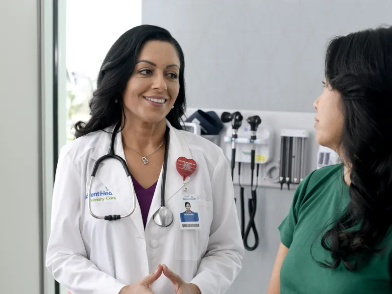 A Primary Care+ Physician Speaks to a Patient in an Exam Room 