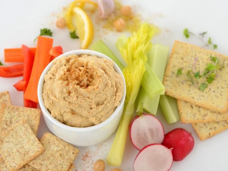 Dish of garmanzo hummus surrounded by crackers and vegetables