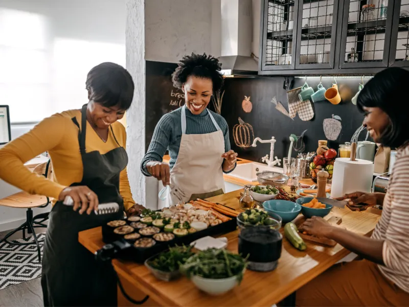 Three women preparing food in a kitchen.