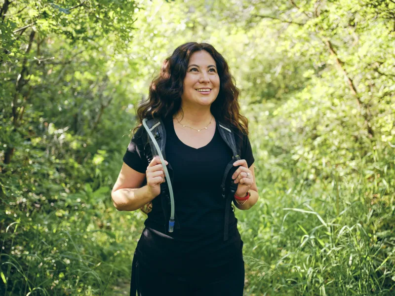 A woman on a hike while wearing a Camelbak backpack.