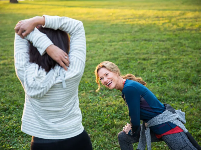 Two friends stretching in the in park during a sunny morning. 
