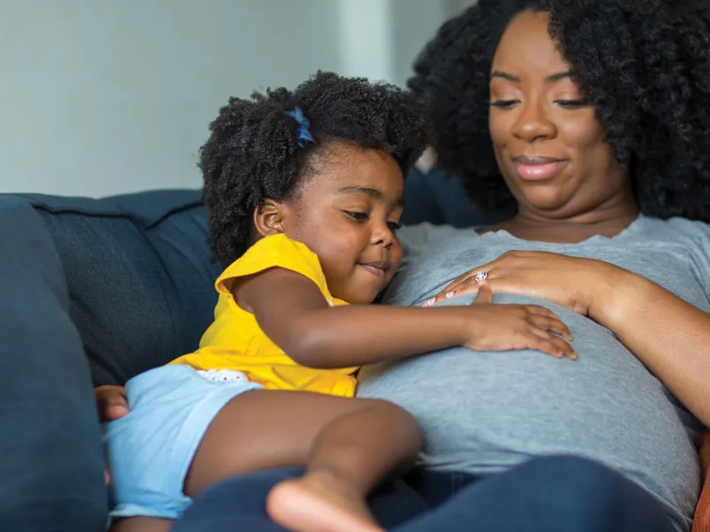 Pregnant Woman on couch with toddler.