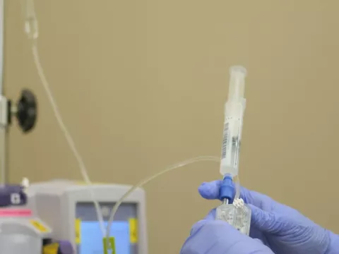 Gloved hands hold up a syringe of bamlanivimab