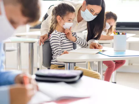 An elementary girl getting help with her assignment from her teacher