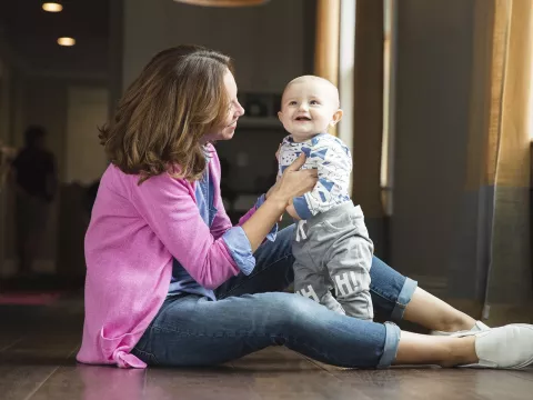 A young mother plays with her toddler on the floor.