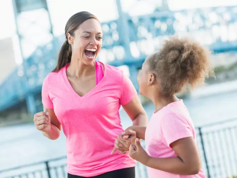Mother and Daughter Laughing as They Jog Together Along The Water Front.