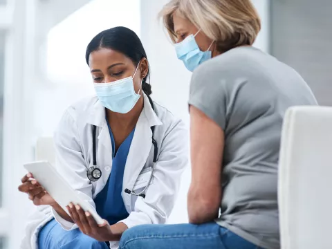 Doctor speaks to her middle aged female patient while going over some notes. 