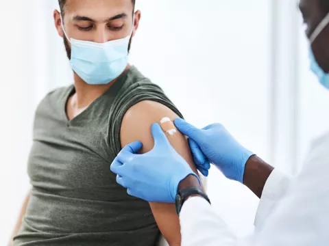 Medical professional putting a bandaid on a man after he received a covid-19 vaccine booster shot