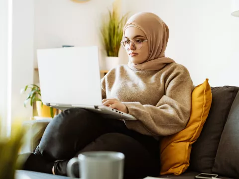 A Woman Looks at a Laptop Computer on Her Couch.