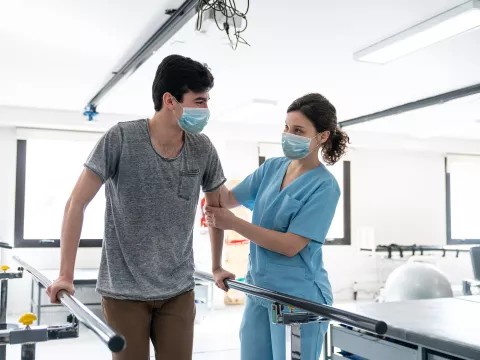 Physical therapist helping a patient through a walking exercise.