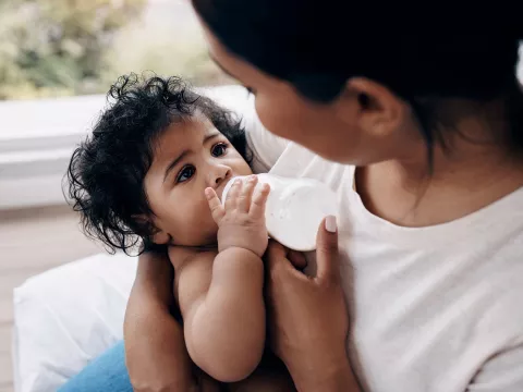 A mother feeding her baby milk in a bottle