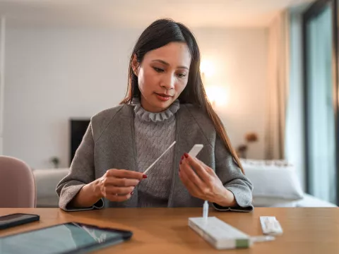 A Woman Checks the Results of an at Home COVID test.