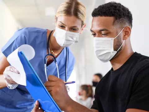 A Patient Fills Out a Form With the Assistance of a Doctor