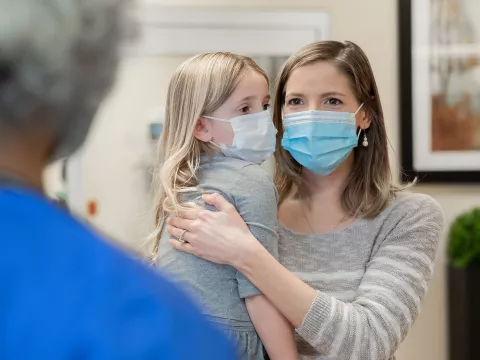A Mother Holds Her Daughter as She Speaks to a Doctor in the Hospital