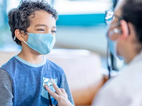 A doctor using her stethoscope on a youthful boy's chest