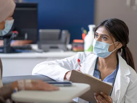 A Doctor Speaks to Her Patient on Her Level in an Exam Room.