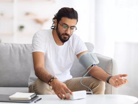 An adult male testing his blood pressure at home