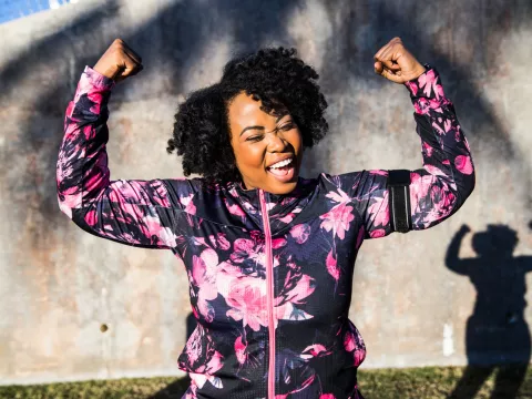 A Woman Triumphantly Flexes Her Arms After a Run in the Park 
