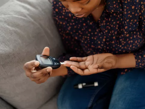A Woman Tests Her Blood Sugar with a Finger Prick Glucose Device