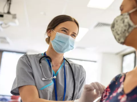 A Nurse Smiles as She Prepares a Patient for an Injection.